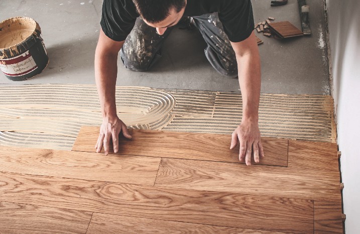 Ein Mann verlegt einen Fußboden aus Holz.